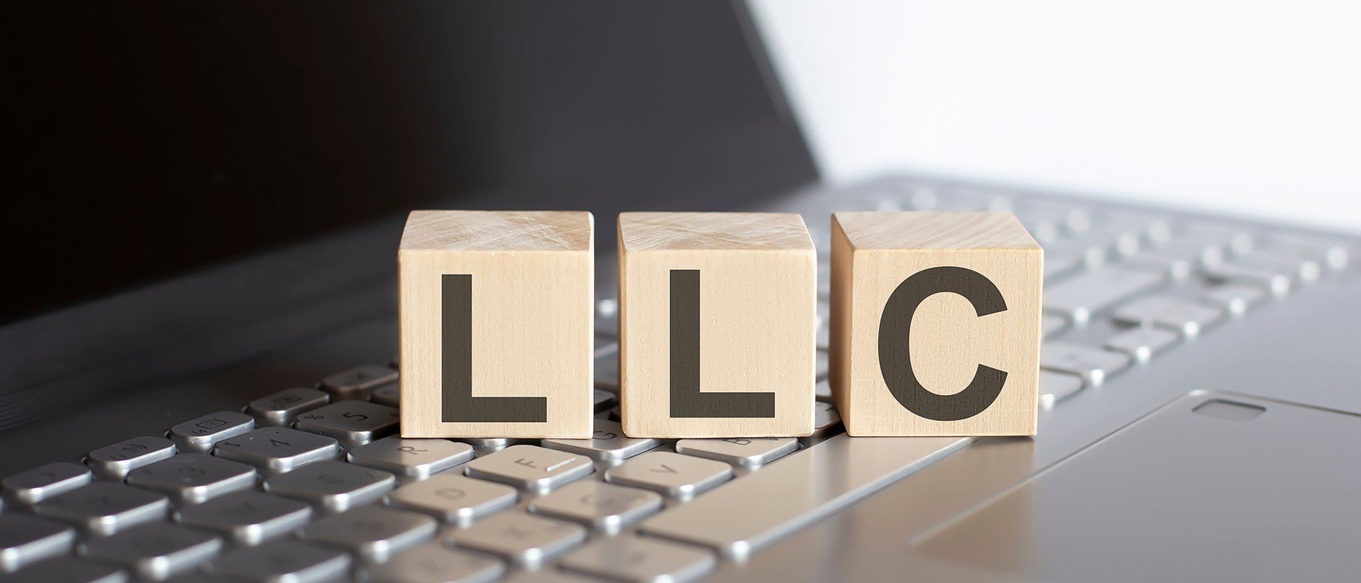 LLC letters in wooden blocks on top of laptop